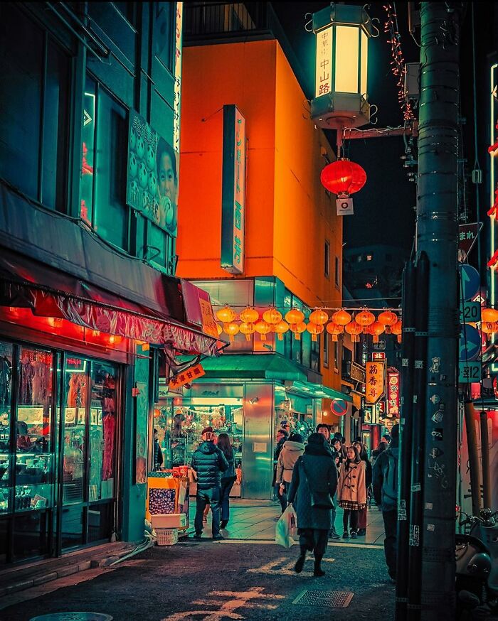 Night street scene in Japan with glowing lanterns and people walking, capturing the beauty of Japan in vibrant colors.