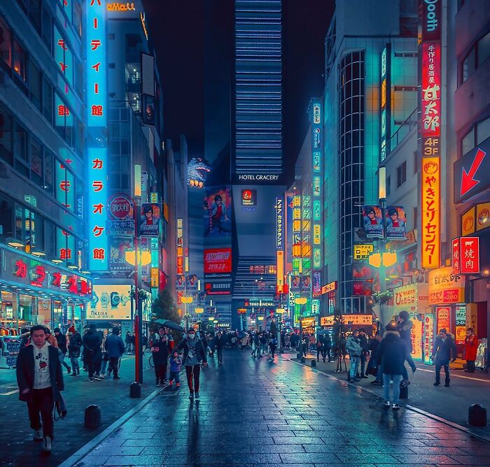 Vibrant nighttime street scene in Japan filled with colorful neon signs and people walking on wet pavement.