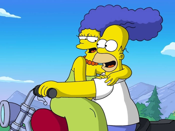 Marge and Homer Simpson hugging each other while riding motorcycle