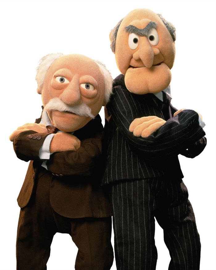 Waldorf and Statler standing next to each other with crossed arms