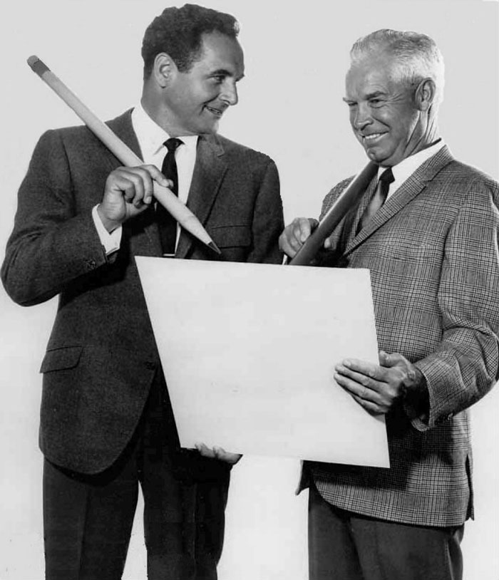 Bill Hanna and Joe Barbera standing next to each other, smiling and holding big pencils 