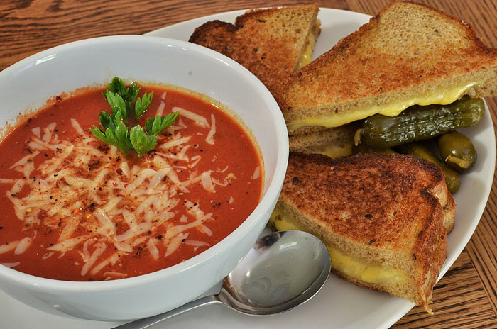 Tomato soup and grilled cheese in a plate on the table