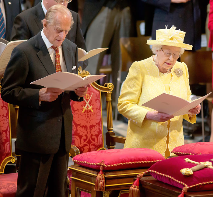 Prince Philip and Queen Elizabeth standing next to each other and reading at church