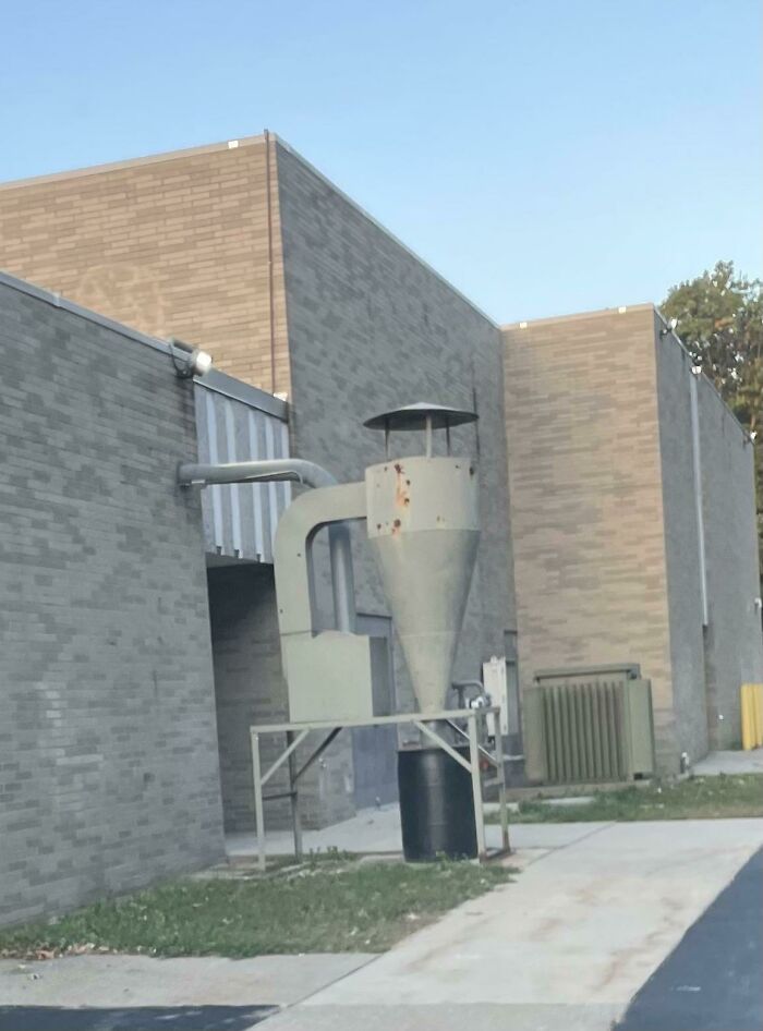 Large Machine Connected To A School Building With A Barrel Underneath It