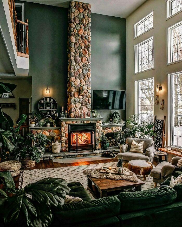 Double-Height Sage Green Living Room Featuring A Stone Fireplace And Lots Of Plants, Winnipeg, Canada