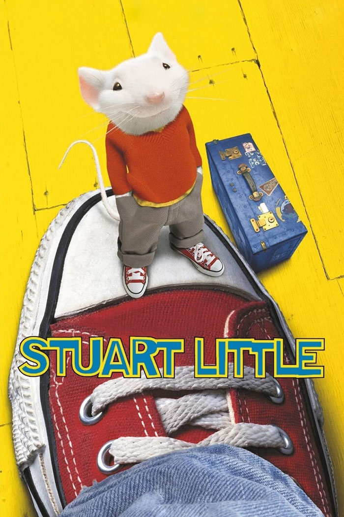 Mouse in red sweater stands on a sneaker with suitcase nearby, representing a classic '90s kids movie.