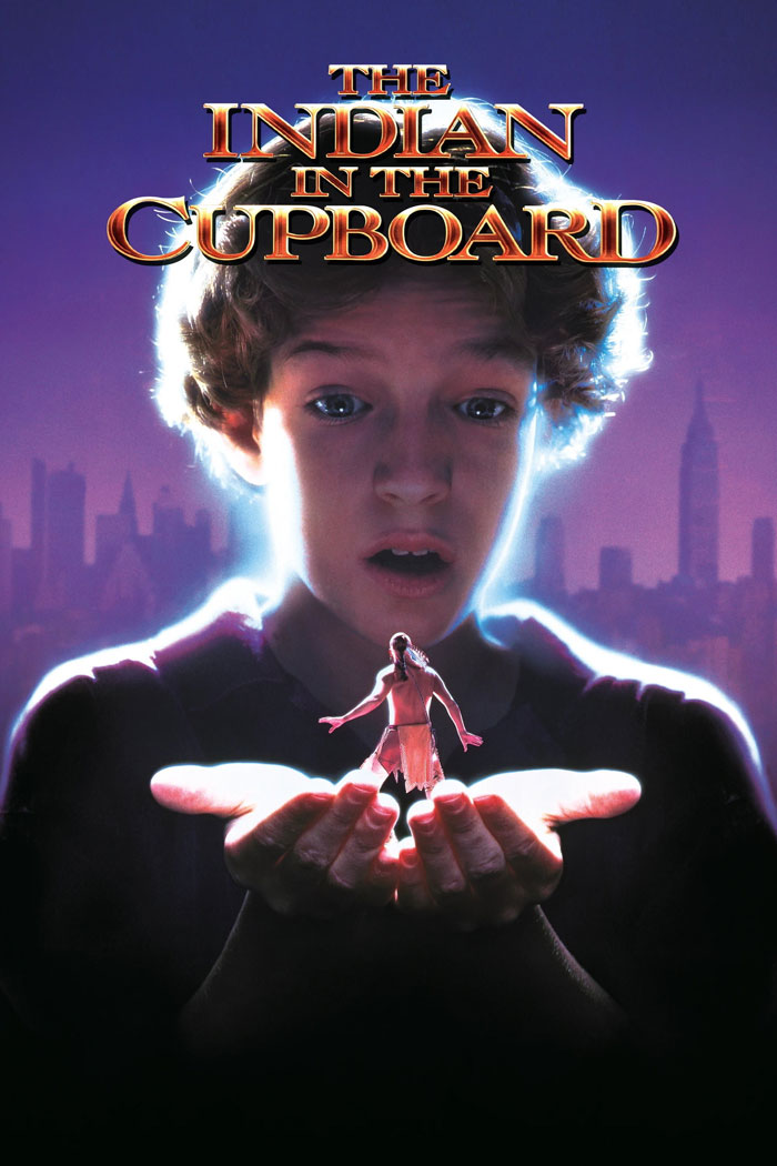Cover of "The Indian in the Cupboard" featuring a boy holding a miniature figure, set against a city skyline.