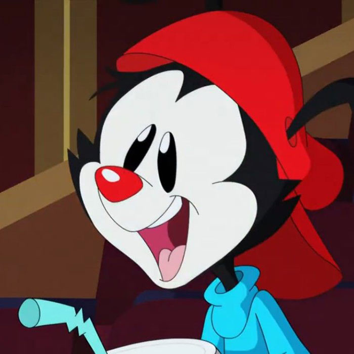 Cute animated character with a red cap and a wide smile, sitting down in a cheerful pose.