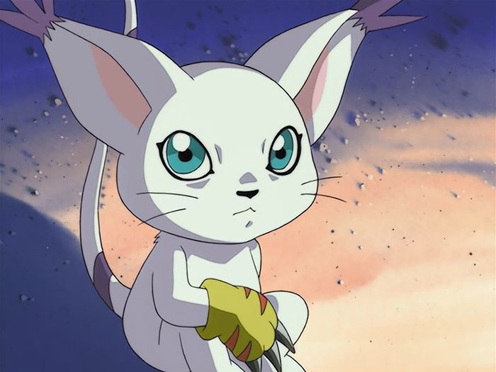 Cute animated character with big ears and blue eyes sitting against a soft, colorful background.