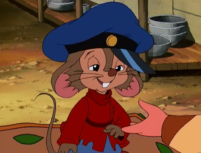 Cute animated character mouse wearing a blue hat and red shirt, smiling charmingly while standing on a table.