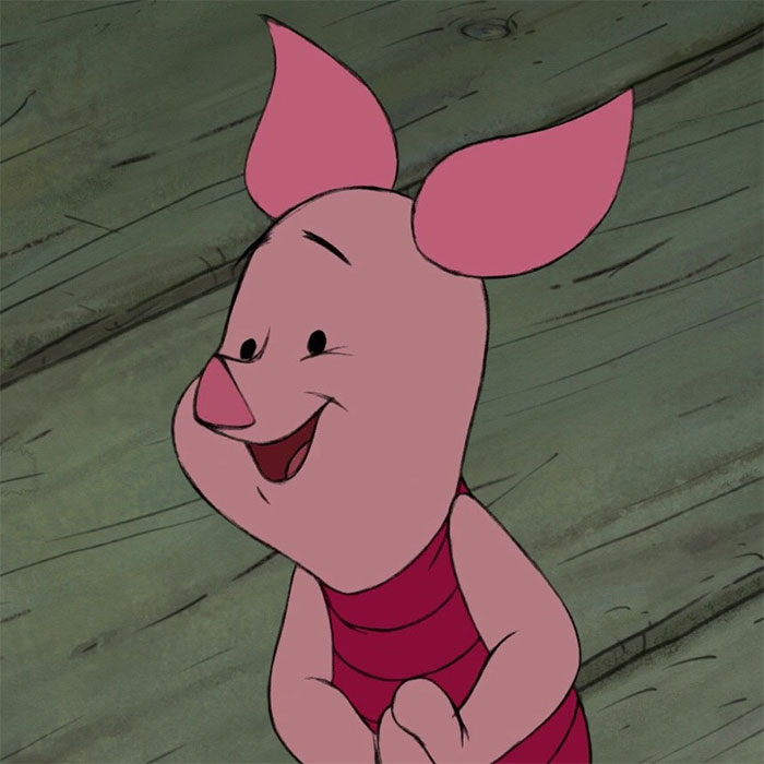Cute animated character with pink ears and stripes, standing on a wooden floor, smiling joyfully.