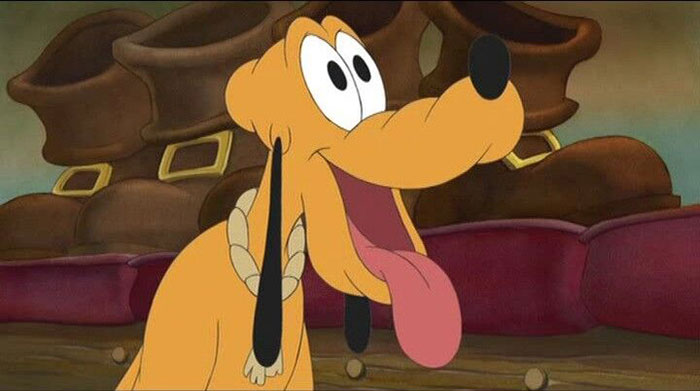 Cute animated character with big eyes and a playful expression, sitting indoors with a red couch in the background.