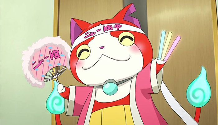 Cute animated character with a cheerful expression, holding colorful items and wearing a decorative headband and robe.