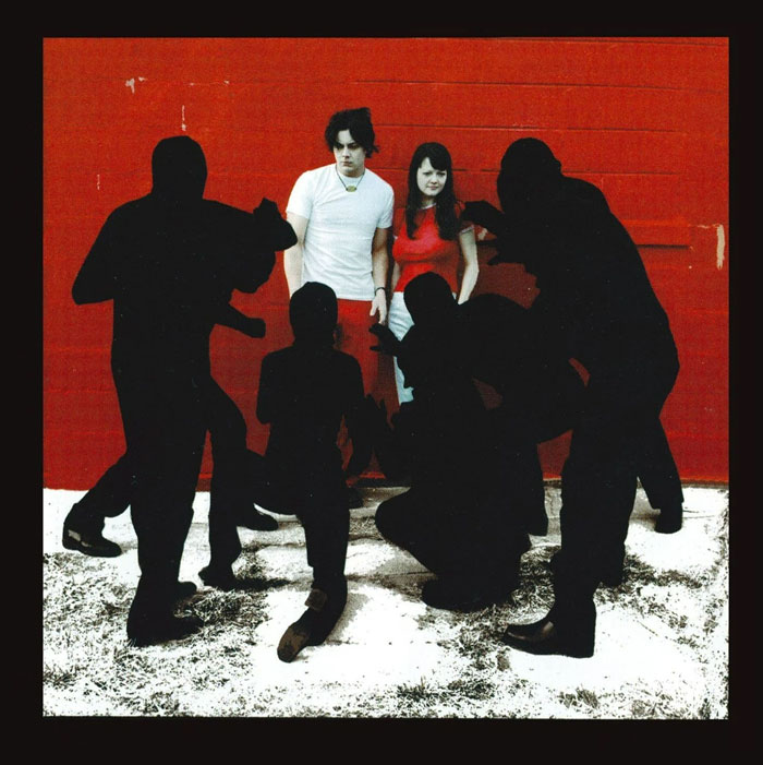 Album cover with a man in a white shirt and a woman in a red top, surrounded by black silhouettes.