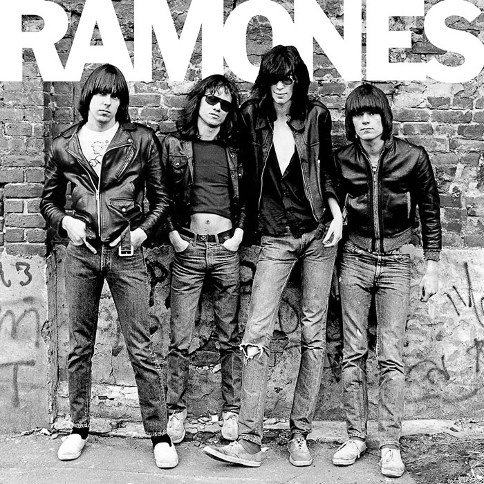 Iconic album cover of a punk band in leather jackets, standing against a graffiti-covered brick wall.