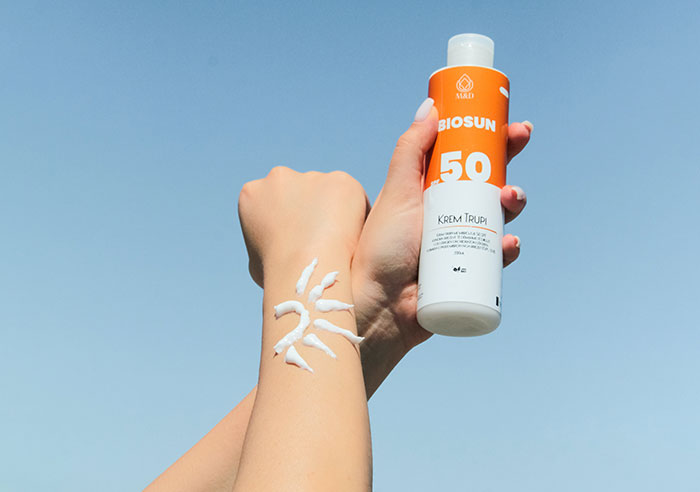 A person holding a bottle of sunscreen in their hand