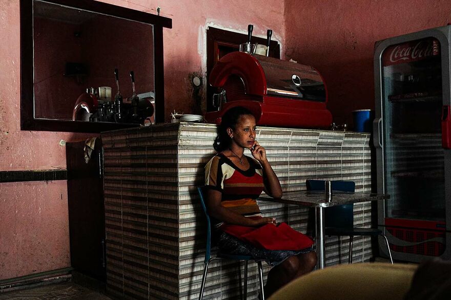 Woman sitting thoughtfully in a dim cafe captured by photographers showcasing beautiful women around the world.