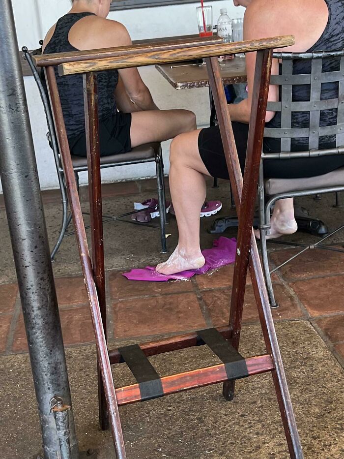 Lady Applying Foot Powder To Her Feet At The Restaurant