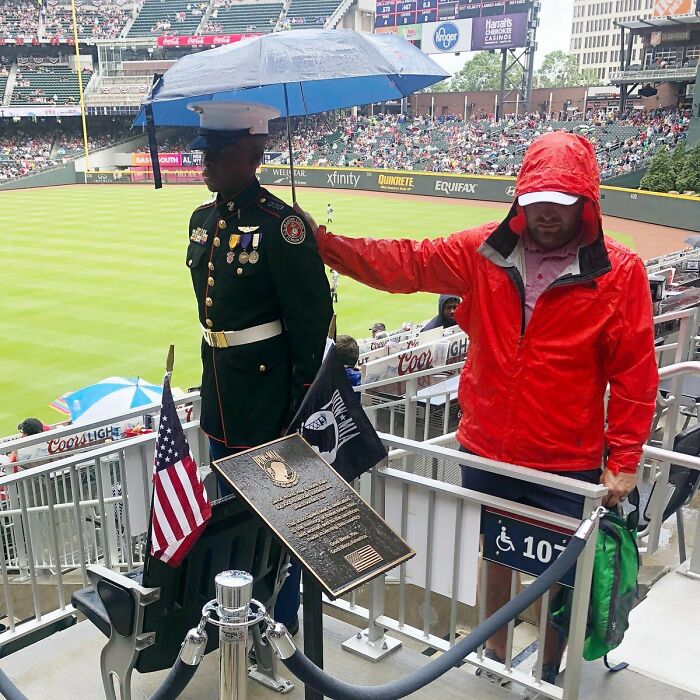 Este hombre sostuvo un paraguas sobre un soldado que estaba parado junto al asiento y la placa dedicados a los 92 mil soldados caídos desde la Primera Guerra Mundial