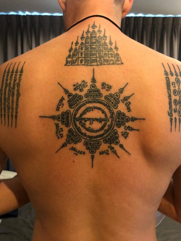 Intricate new tattoo with geometric and script patterns on a person's back.