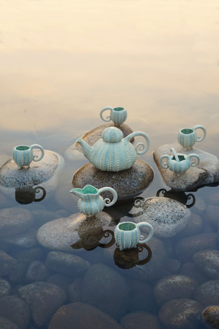 Nature-inspired ceramics set resembling sea urchins displayed on rocks in water.