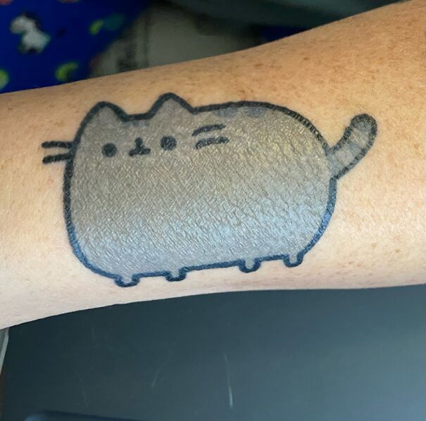 Cute cartoon cat tattoo on arm, showcasing impressive new tattoo design.
