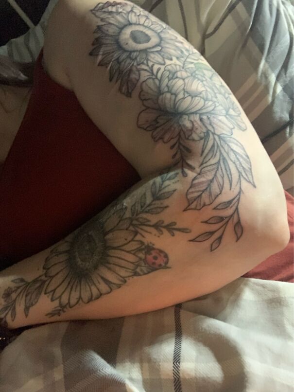 Arm tattoo featuring floral designs and a ladybug, showcasing impressive new body art.