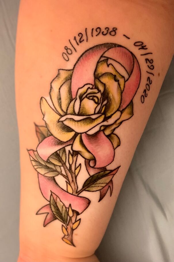 Pink ribbon and yellow rose tattoo with memorial dates, showcasing impressive new ink.