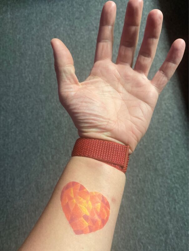 A geometric heart tattoo on inner forearm near red wristband, showcasing impressive new tattoo design.