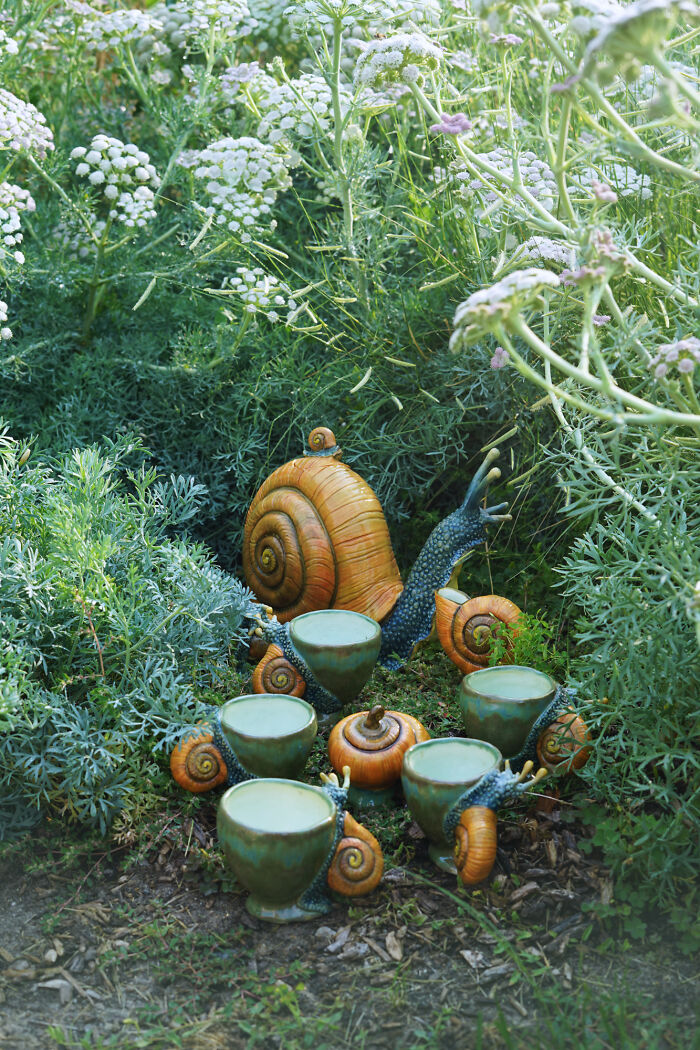 Nature-inspired ceramics featuring snail-shaped sculptures in lush green garden.