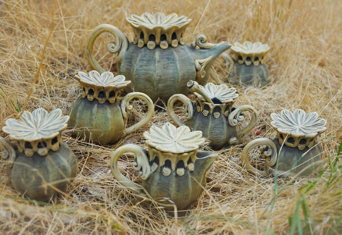 Nature-inspired ceramic tea set displayed on dry grass.