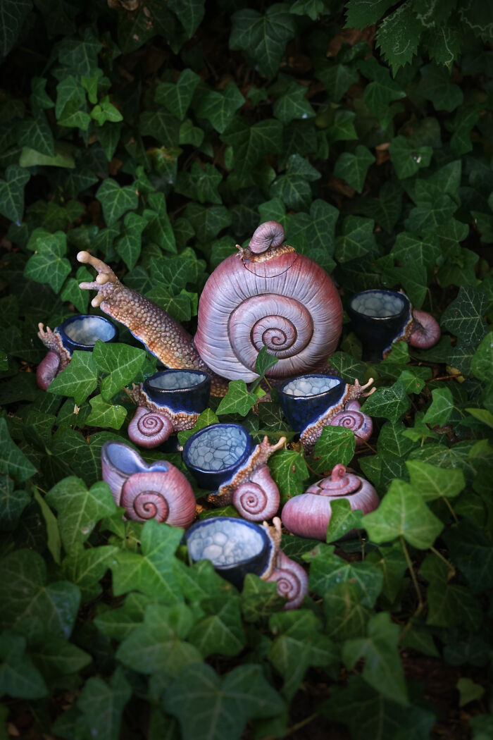 Nature-inspired ceramics resembling snails, set among lush green leaves, highlighting artistic creativity and detail.