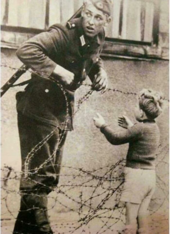 An East German Soldier Ignores Orders To Let No One Pass And Helps A Boy, Who Was Found On The Opposite Side From His Family, Cross The Newly Formed 'Berlin Wall'- 1961