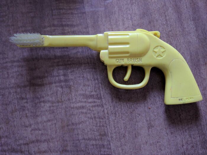 Este viejo cepillo de dientes con cerdas en el extremo del cañón de una pistola de juguete - El gatillo incluso hace clic cuando se tira