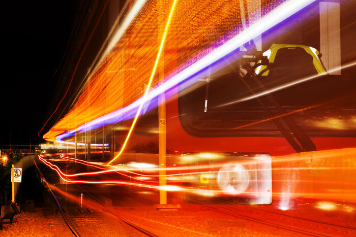 Long exposure of a tram at night, creating vibrant, otherworldly light trails on the tracks.