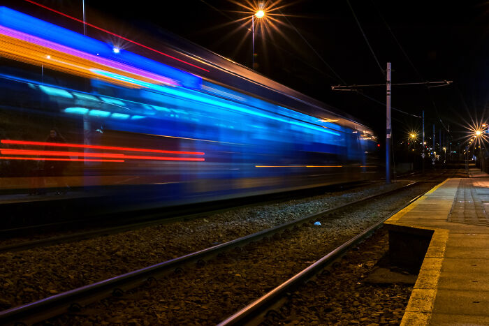 Long exposure photo of a tram at night, with colorful lights creating a surreal, otherworldly effect.