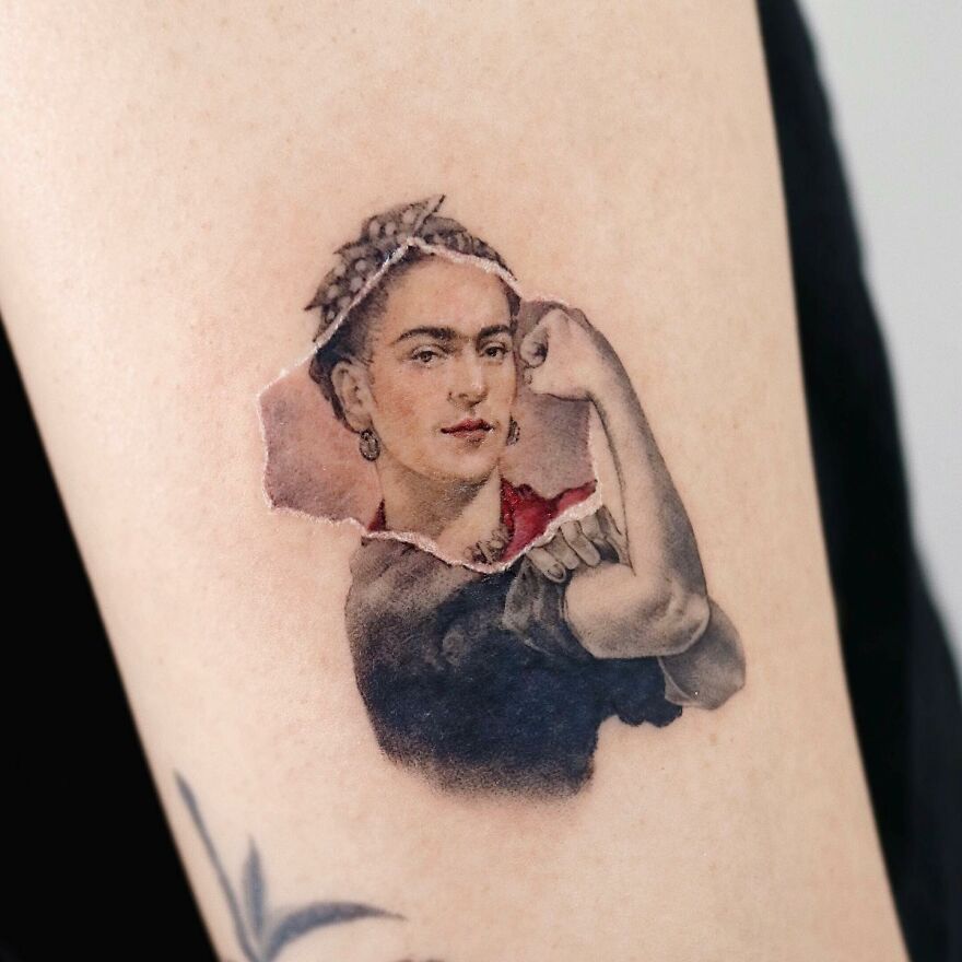 Painting-like tattoo of a woman flexing her arm, showcasing artistic detail and realism.