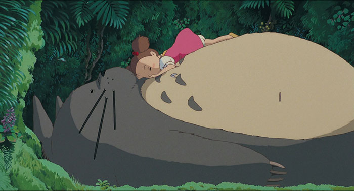 A girl rests on a cute animated character in a lush forest.