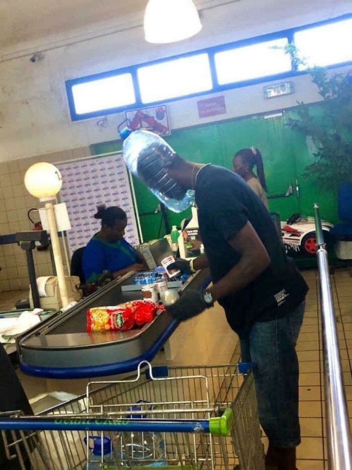 Man in a cash register with a plastic bottle on his head 