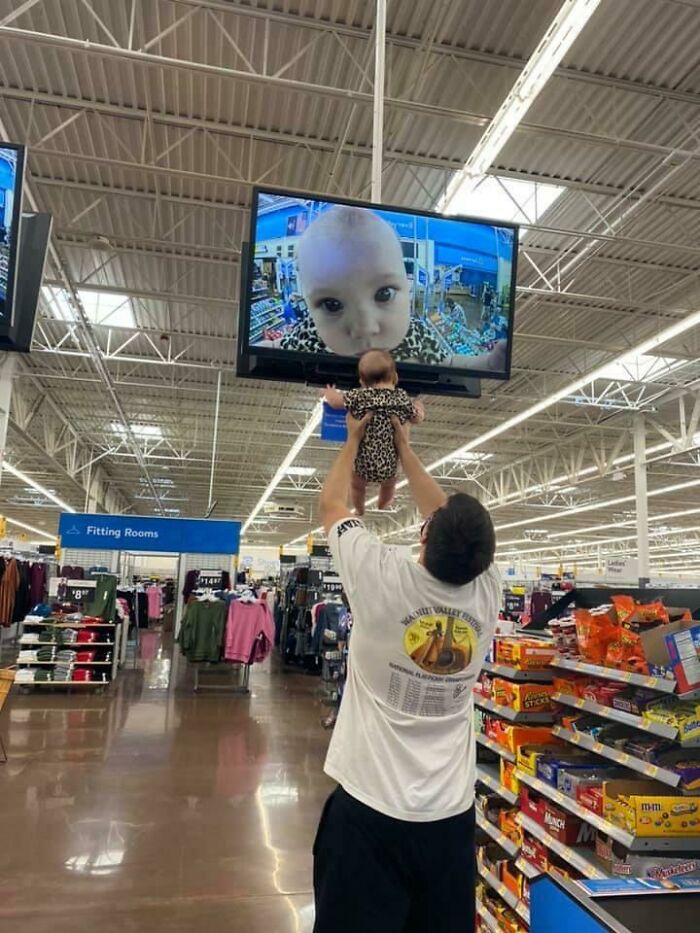Man showing his baby to a security camera 