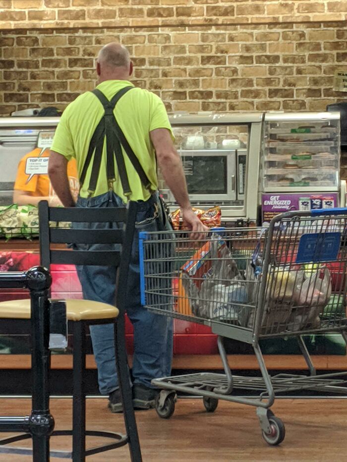 Man standing with a cart many suspenders on his pants 