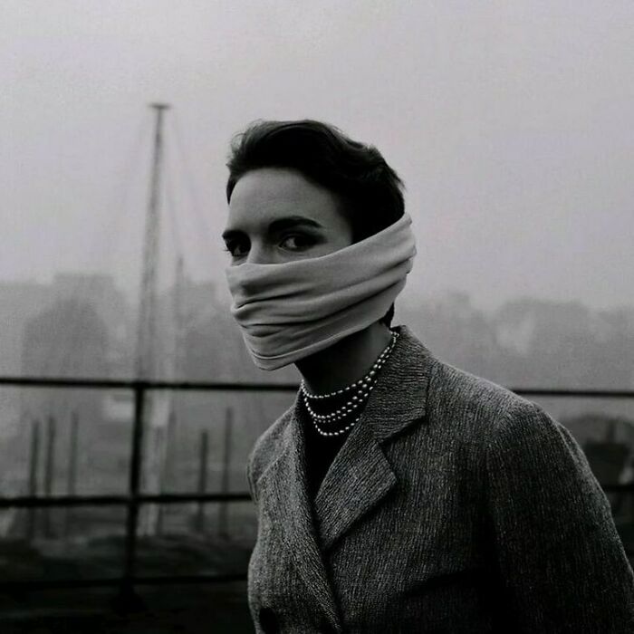 A Woman With Strings Of Pearls Around Her Neck Uses Her Scarf To Mask Her Nose And Mouth From The Great Smog In | London, 1952, Which Quickly Killed 12,000 Over 5 Days