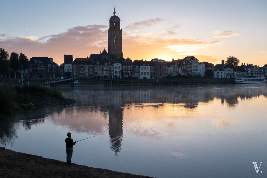 A Boy Fishing In The Ijssel River. Deventer, The Netherlands