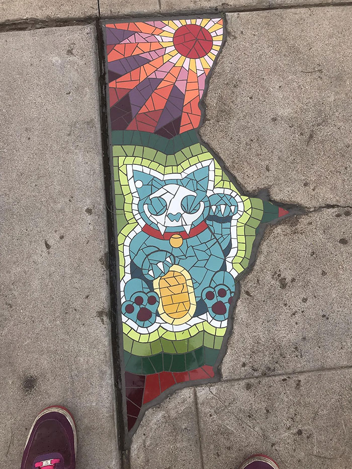 Esta grieta en el pavimento rellenada con un retrato de un gato en mosaico
