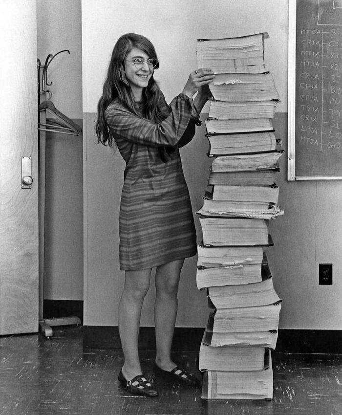 Margaret Hamilton, la principal ingeniera de software de la NASA para el programa Apolo, junto al código escrito a mano que llevó a la humanidad a la Luna en 1969