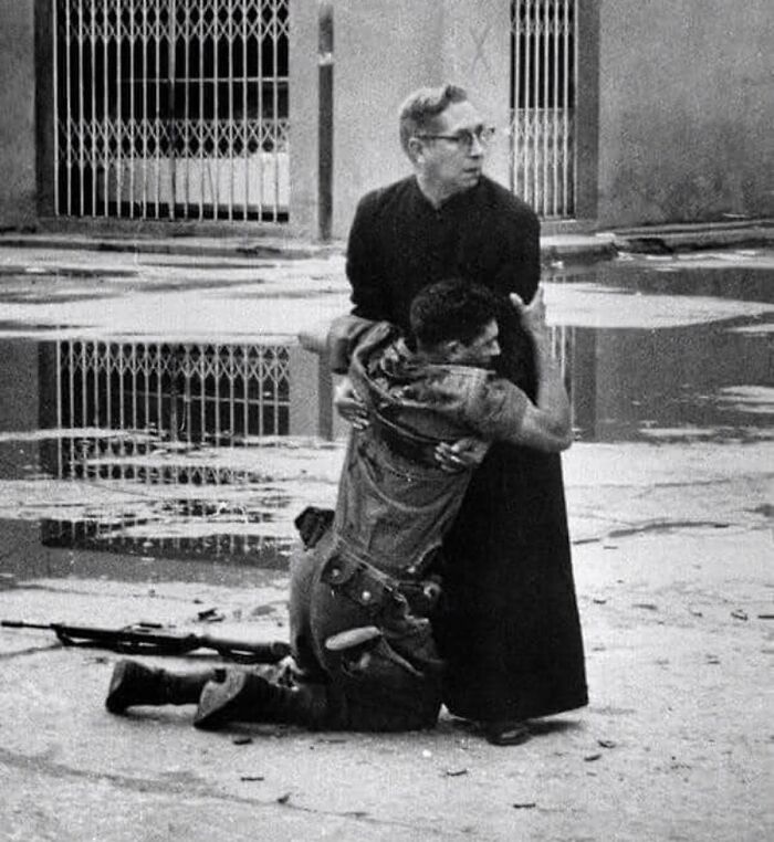 A Priest Holds A Dying Soldier Whilst Bullets Are Fired Around Them | Venezuela, 1962