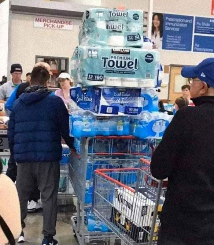 Person standing with a cart filled with water and toilet paper 