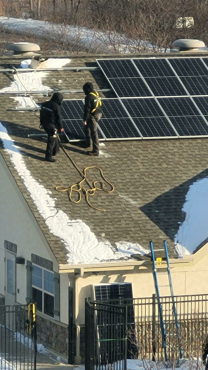 Installing Solar Panels. One Guy Has A Harness But Isn't Tied Off, The Other Has No Harness. The Rope Is For Attaching To The Panels, But Is So Long That The Panel Would Hit The Ground