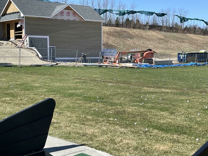 Construction Site On The Side Of A Driving Range With No Protective Netting Or Any Sort Of Barrier. The Area The Crew Is Working Is Covered In Golf Balls