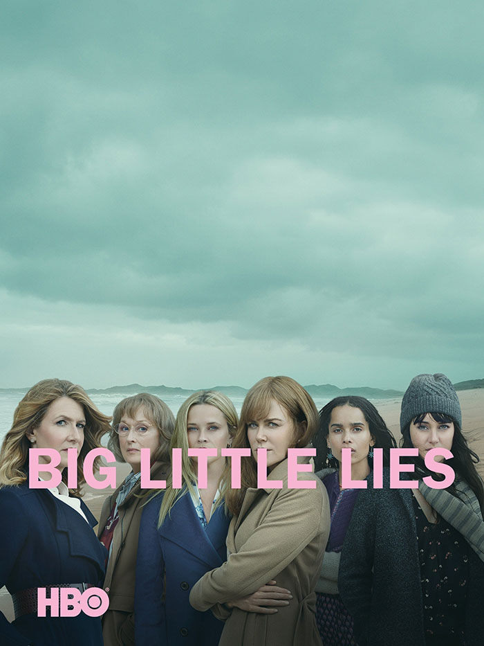 Main cast of "Big Little Lies," an HBO TV show, standing together on a beach under a cloudy sky.